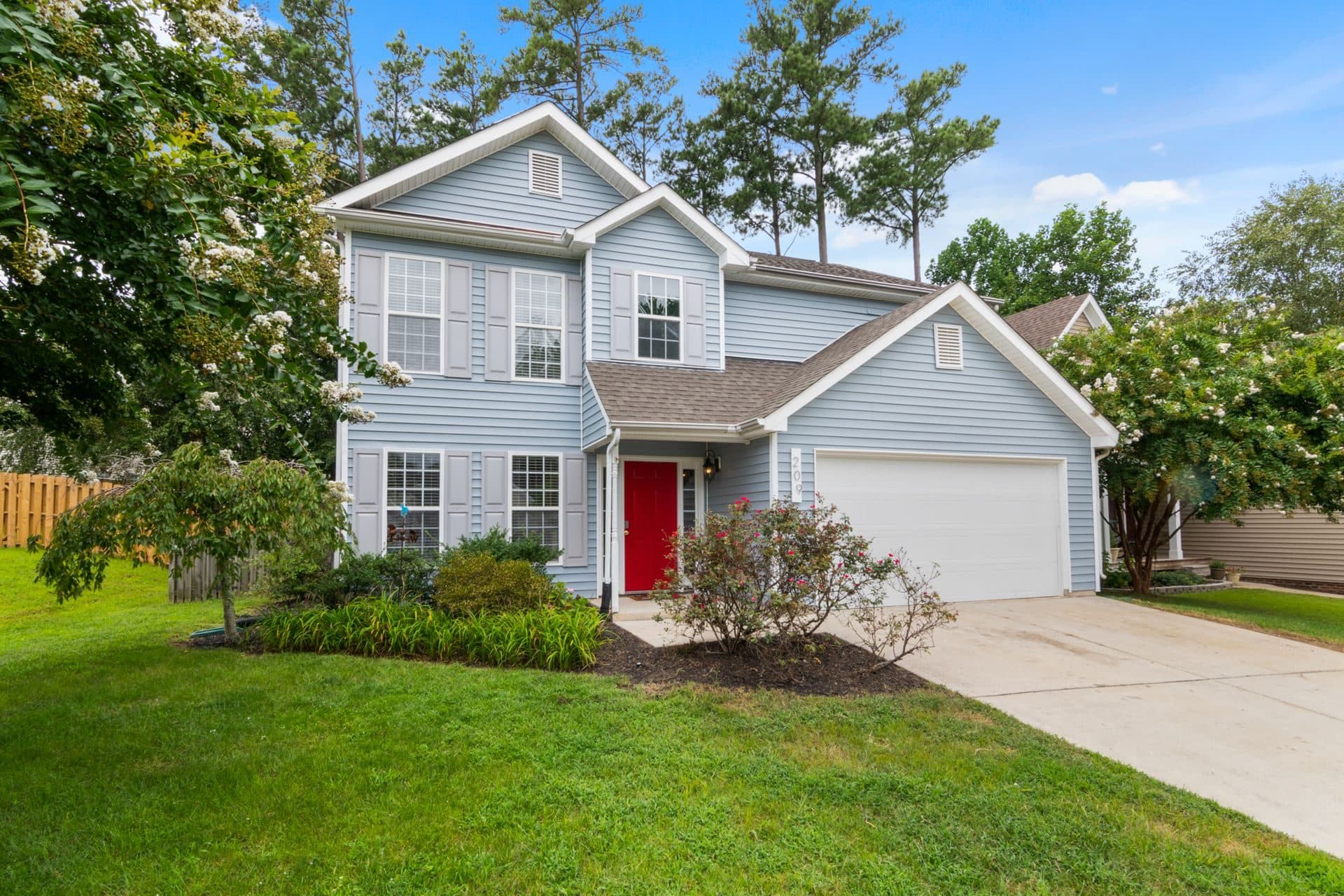 A freshly painted two-story home with gray siding, crisp trim, and a tidy front lawn