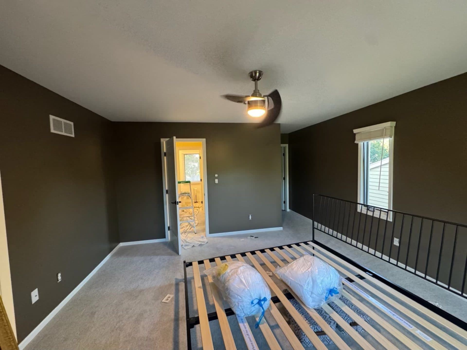 An interior room painted a deep olive green, the carpet papered off and floors protected mid-job
