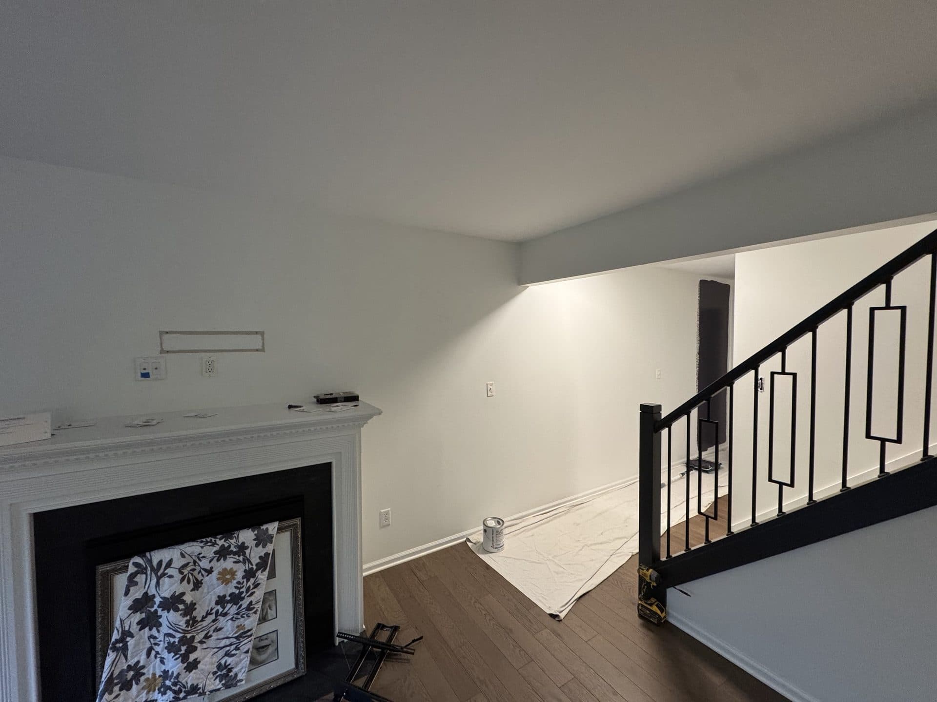 A freshly painted living room with light gray walls, a white fireplace, and clean trim