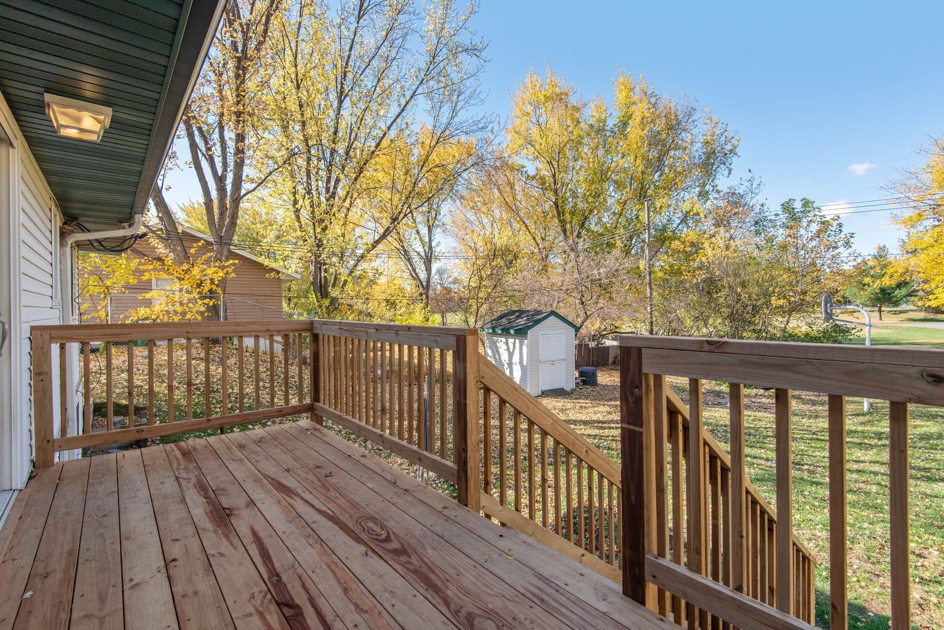 A wood deck with a fresh stain and clean railings in a backyard