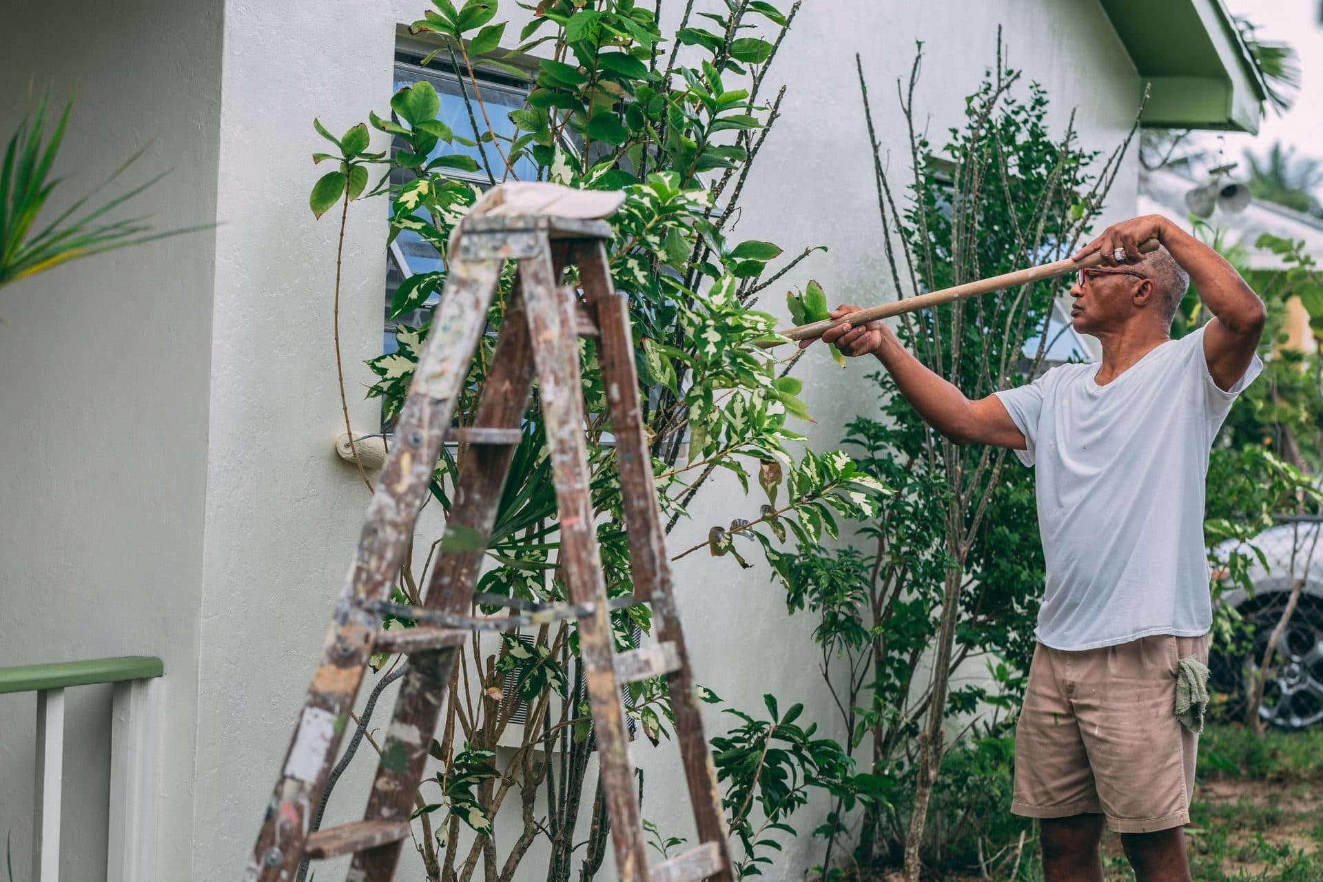 A painter on a ladder applying a fresh coat to the exterior of a home