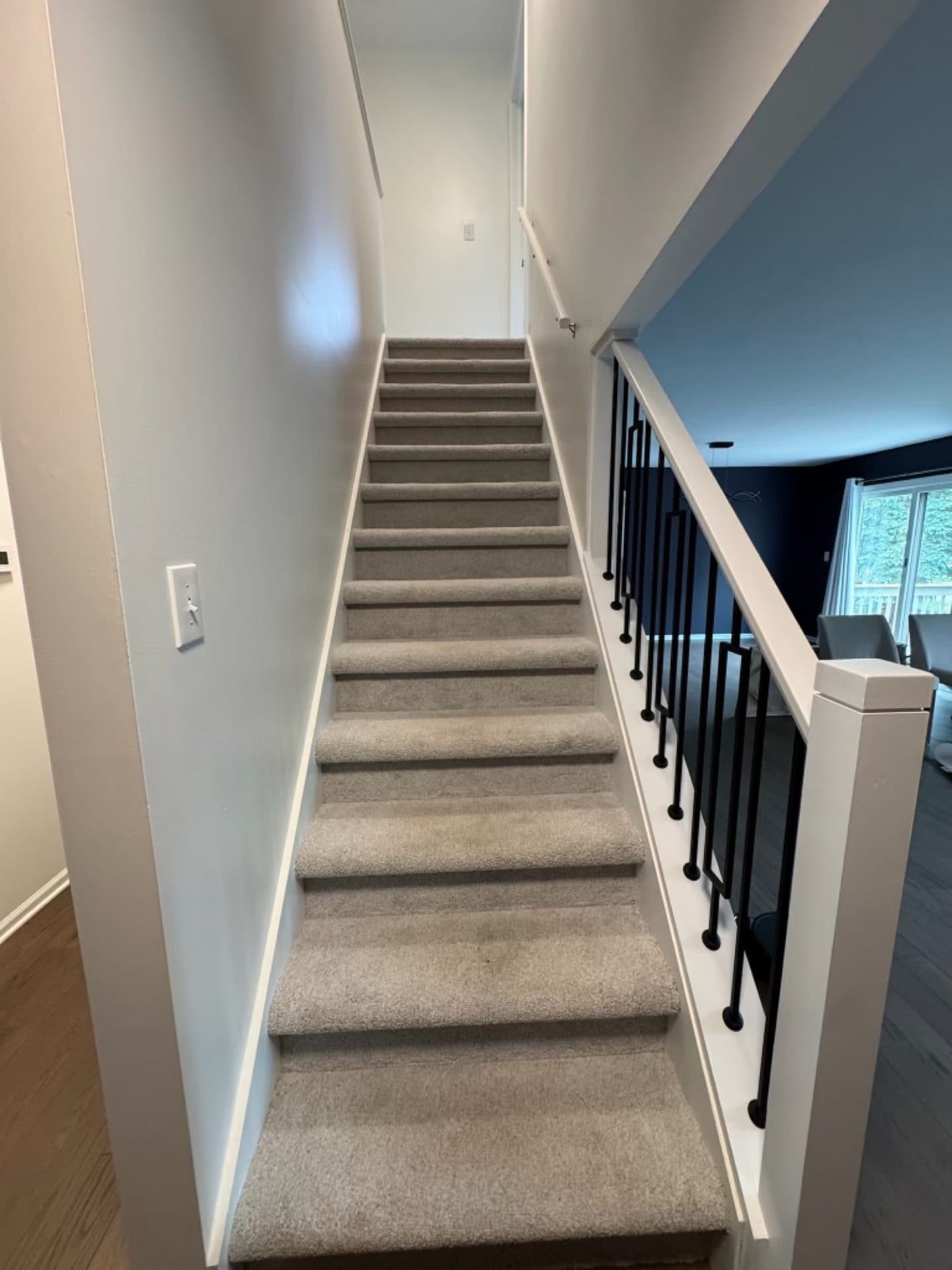 A repainted staircase and upstairs hallway in light gray with black metal railings