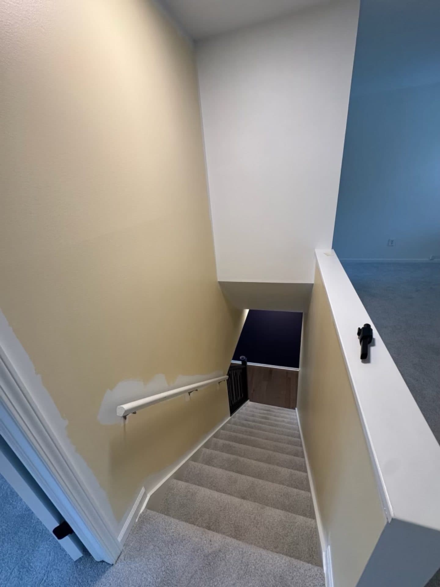 A stairwell landing with a dark accent wall next to a warm neutral wall